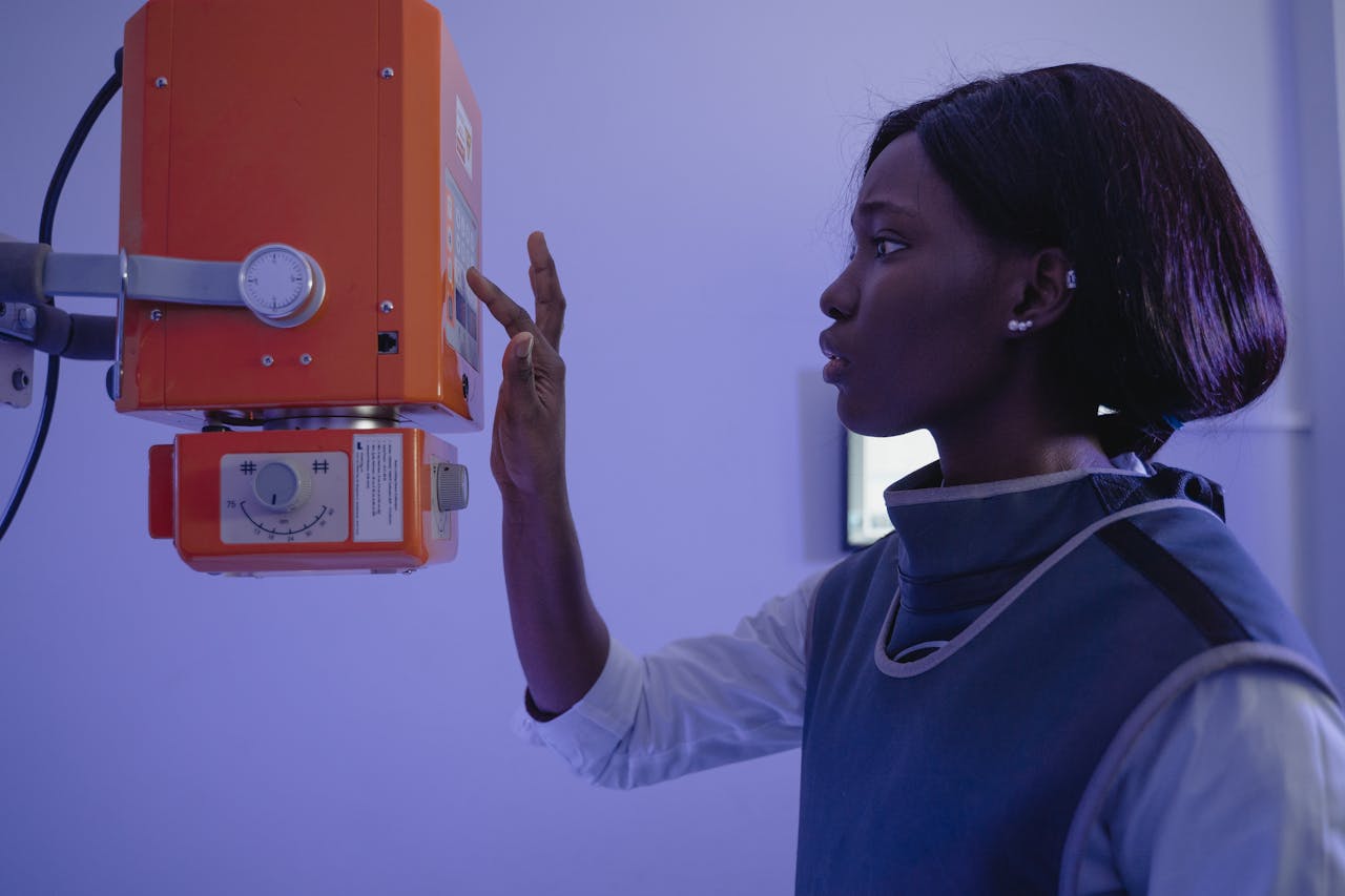 African American female healthcare worker using X-ray equipment in a clinical setting.