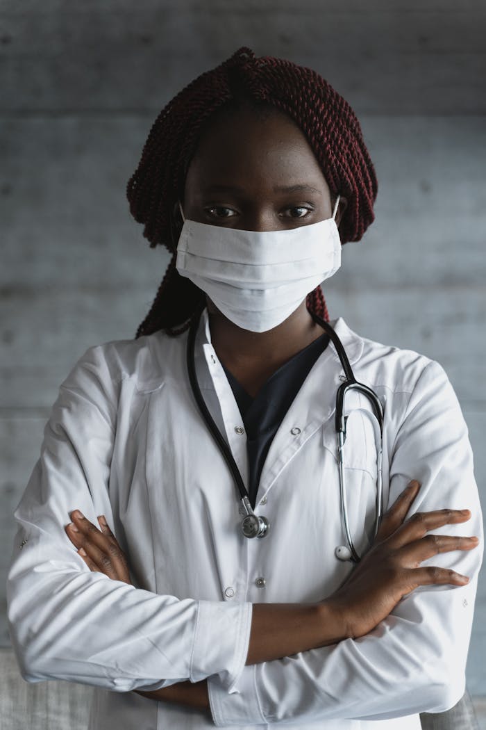 Portrait of a confident female doctor wearing a mask and stethoscope, arms crossed.